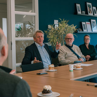 Meerdere mannen zitten aan tafel in een vergaderruimte