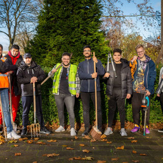 Waalhandjes staan op een rij met tuingereedschap in hun handen