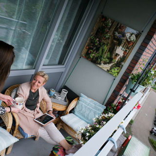 Twee dames drinken samen een kopje koffie op het balkon