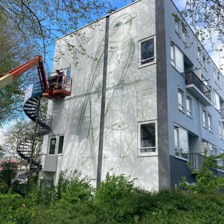Muurschildering van een vogel wordt op een woongebouw aangebracht