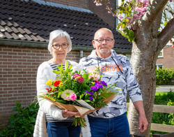 Bewoners staan met een bos bloemen op straat