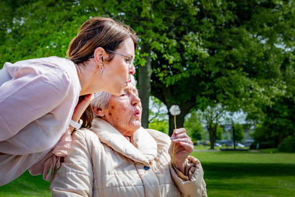 Vrouw en oudere vrouw blazen tegen een paardenbloem
