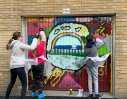 Meisjes sprayen graffiti op een garagedeur