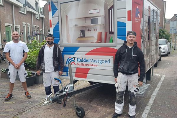Drie schilders staan bij een bouwkeet