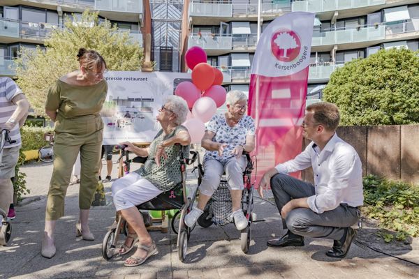 Directeur Cees Tip praat met oudere vrouw met een rollator