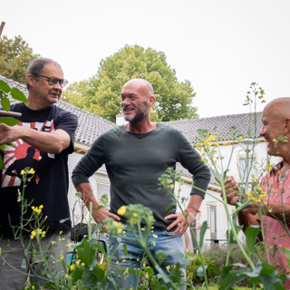 Medewerker Intermaris staat met twee bewoners in de moestuin
