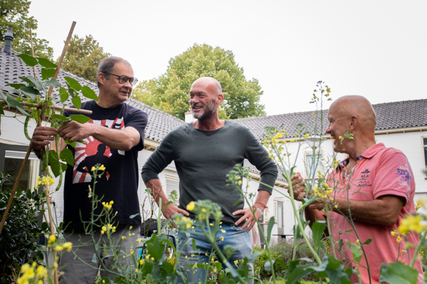 Medewerker Intermaris staat met twee bewoners in de moestuin