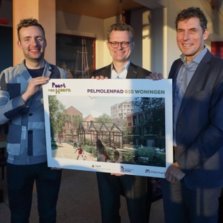 Drie bestuurders staan met een bord met nieuwbouwplannen in hun handen