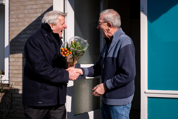 Bewoner ontvangt een bos tulpen van de directeur tijdens complimentendag