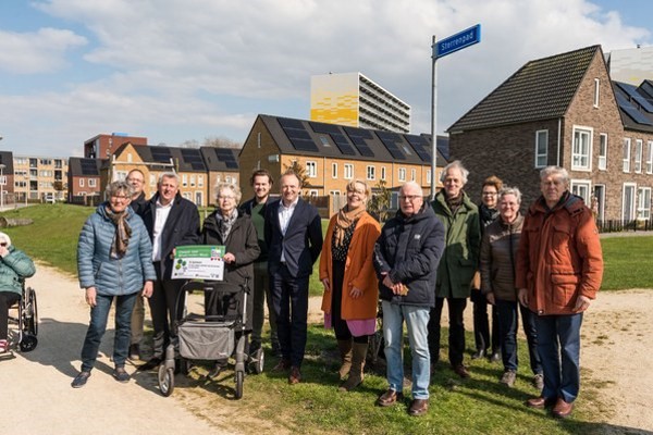 Meerdere bewoners staan op een rij buiten in de wijk