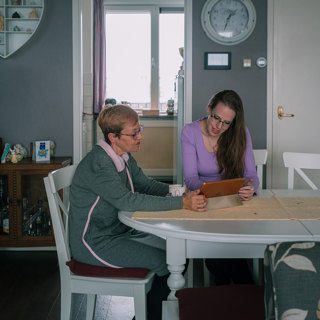 Twee bewoners kijken samen aan tafel op een tablet