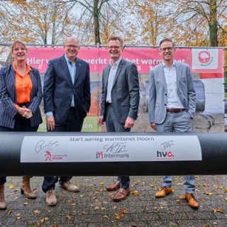Directeuren en wethouders staan bij leidingenbuis voor start Warmtenet