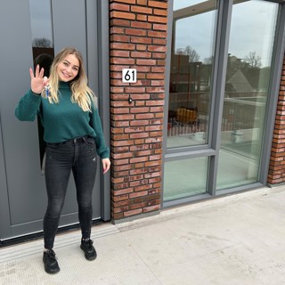 Bewoonster staat voor haar nieuwe woning met de sleutel in haar hand