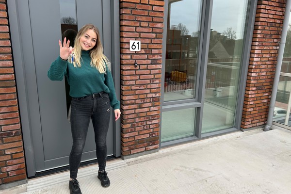 Bewoonster staat voor haar nieuwe woning met de sleutel in haar hand