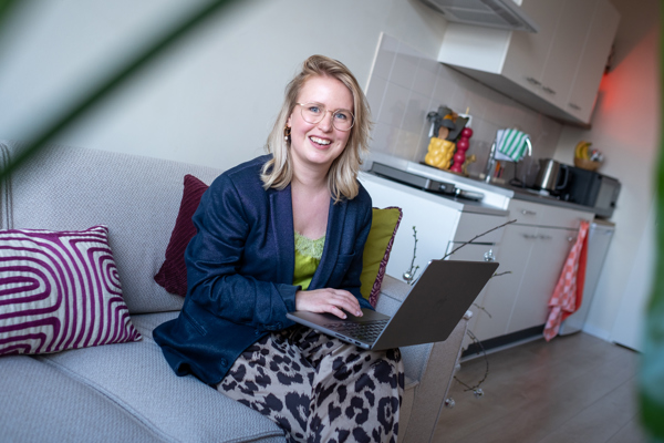 Bewoonster in haar woning op de bank met laptop