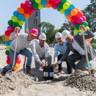 Directeuren plaatsen een tijdcapsule in de grond bij een nieuwbouwproject