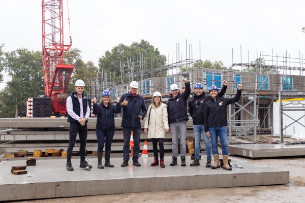Groep mensen staat met een bouwhelm op op een betonnen plaat op de bouwplaats