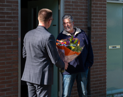 Directeur Cees tip geeft bloemen aan een bewoner