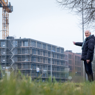Bewoner staat buiten voor woongebouw dat nog gebouwd wordt