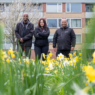 Drie medewerkers van buurtteam Purmerend Oost staan voor een woongebouw