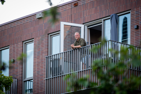 Bewoner staat op zijn balkon naar buiten te kijken